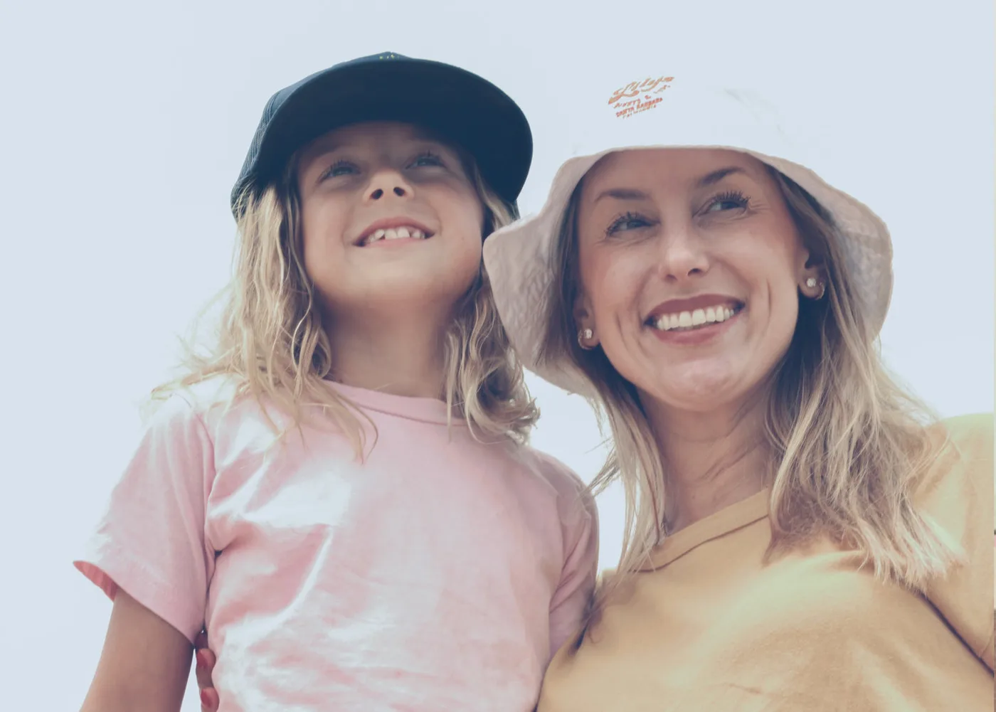 A woman and a child at the beach wearing Lily's bucket hat and cap